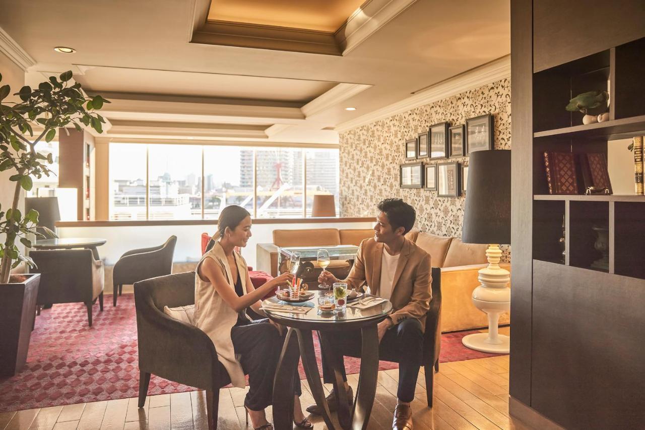 فندق كوبي ميريكين بارك أورينتال كوبه المظهر الخارجي الصورة The photo shows a cozy indoor setting, likely a cafe or restaurant, with two people seated at a small round table. They appear to be enjoying a meal or drinks together, with food and glasses in front of them. The interior features large windows letti