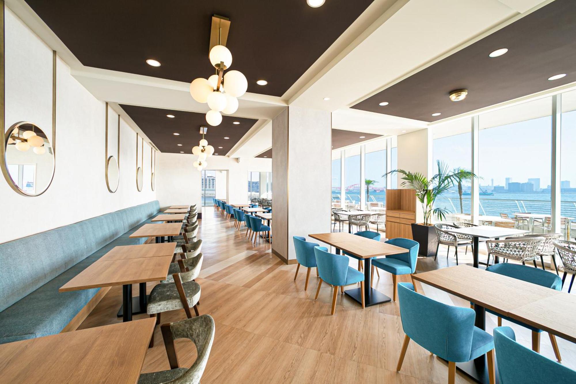 فندق كوبي ميريكين بارك أورينتال كوبه المظهر الخارجي الصورة The photo shows the interior of a modern restaurant or café, featuring a spacious and bright atmosphere. The design includes large windows that provide a view of the outside, allowing natural light to fill the space. There are various tables made of 