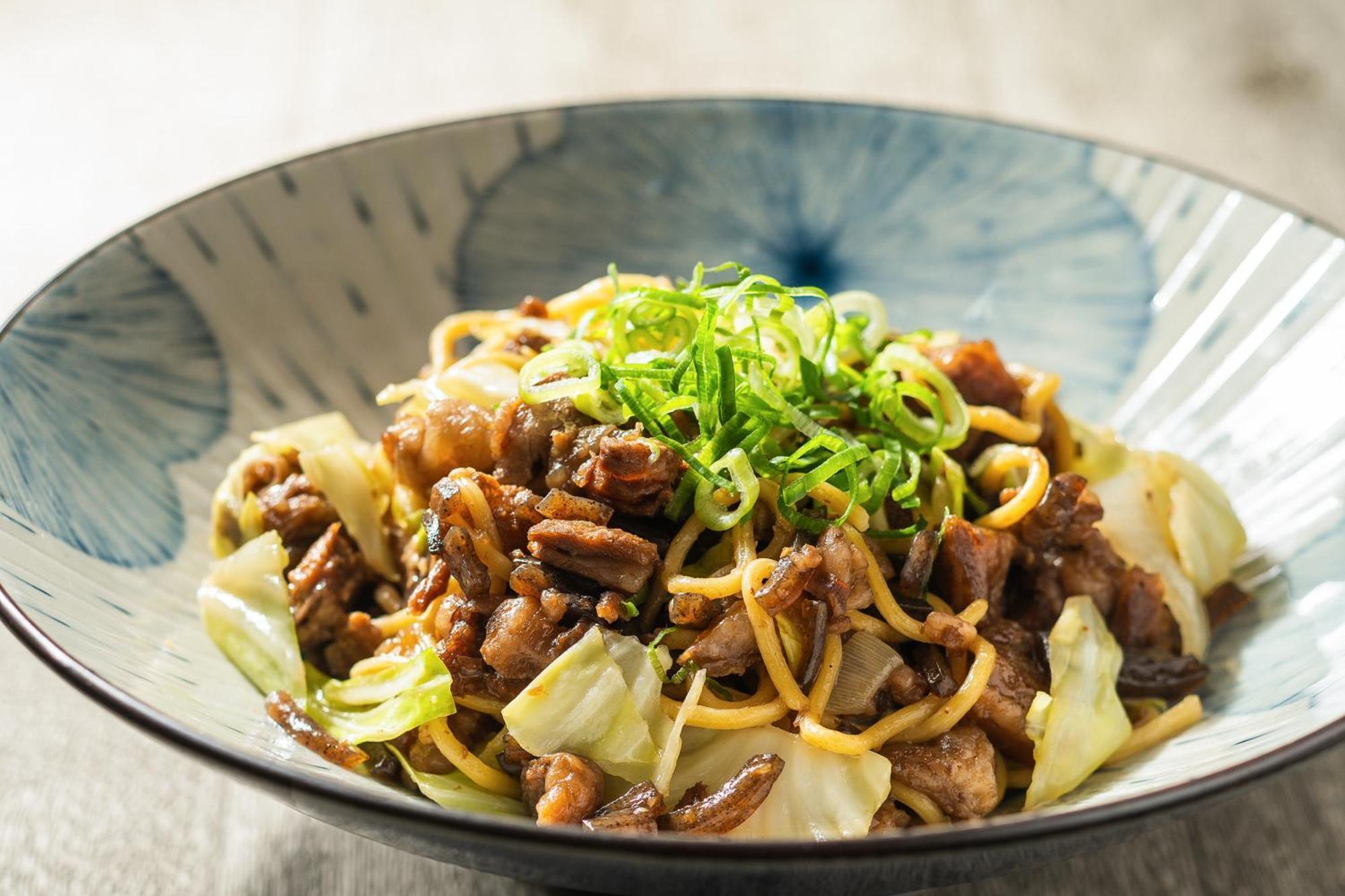 فندق كوبي ميريكين بارك أورينتال كوبه المظهر الخارجي الصورة The photo shows a serving of a dish in a stylish bowl. The dish features a mix of stir-fried noodles, likely accompanied by pieces of meat and vegetables. There is visible cabbage included, and it is garnished with finely chopped green onions on top.